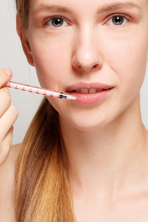 Attractive woman at plastic surgery with syringe in her faceの写真素材