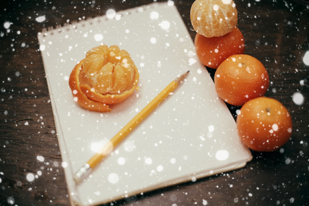 winter, christmas, food concept- Tangerines notebook pencil coffee on old wooden over snow backgroundの写真素材