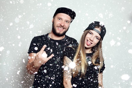 winter, christmas, people, happy concept- fashion beautiful couple together. Tattoo Hipster boy and girl. Bearded young man and blonde over snow backgroundの写真素材