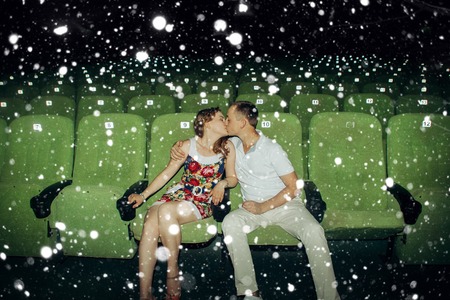 love, winter, christmas, people concept- Stylish couple having romatic moment in a movie theater over snow backgroundの写真素材