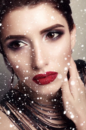 winter, christmas, people, beauty concept- Beautiful girl with perfect skin and wine lips, beautiful hair and jewelry design. Picture taken in the studio. over snow backgroundの写真素材
