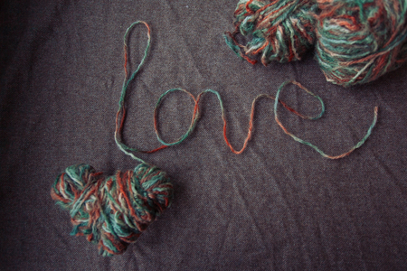 holidays, love and valentines day concept - The word love written of wool yarn on a brown background. Valentines Day backgroundの写真素材