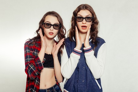 technologies, emotions, lifestyle, people, teens and friendship concept - Two attractive smiling girl in a 3d-glasses slightly tilted to the right. Isolated on white backgroundの写真素材