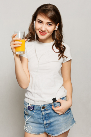spring,health, people, youth and beauty concept - head and shoulders portrait of attractive caucasian smiling woman studio shot drinking orange juice face skin. Woman juice glass . Female model hold orange juice glassの写真素材