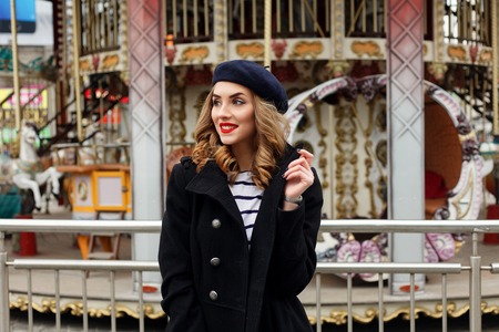 emotions, people, beauty and lifestyle concept - Girl Frenchwoman, against a merry-go-round. Street...