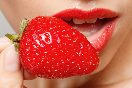 people, emotions, natural, food, beauty and lifestyle concept - Sexy Woman Eating Strawberry. Sensual Lips. Manicure and Lipstick. Desire. Beauty Girl Sexy Lips with Strawberry. white teethの写真素材