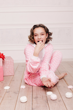 winter, christmas, holiday, sweets, birthday, celebration and children concept- Cute little girl pajama with sweets sitting on the floor, happy childhood concept. girl gifts, soft dog, soap bubbles.の写真素材