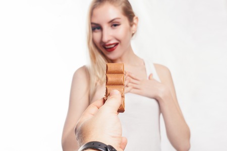 health, people, food and beauty concept - Lovely smiling teenage girl eating chocolate. girl is...