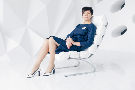 people, portrait and business concept - Happy woman relaxing on her couch at home in the sitting room. Happy mature female on sofa. Smiling middle woman at homeの写真素材