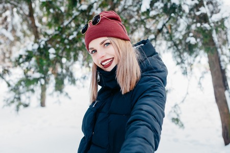 winter, christmas, emotions, people, lifestyle and beauty concept- Christmas girl outdoor portrait. Winter woman blowing snow in a park. Flying Snowflakes. Sunny day. Backlit. Good moodの写真素材