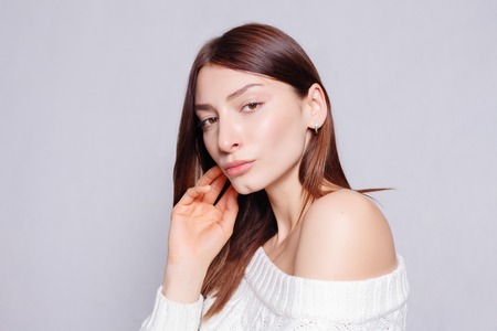people, health and lifestyle concept - Beautiful woman face close up portrait young studio on gray. The young woman's portrait with happy emotions, smile.の写真素材