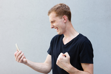 fashion, style, emotions and people concept - Close up portrait of a redhead of a beautiful manly guy with freckles. rejoices at the winning bet in the bookieの写真素材