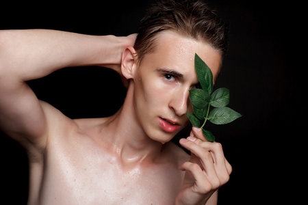 people, skincare and beauty concept - Wet young man with black hair on a black background. Portrait male with shaved chest . Men's skin care. Ripped muscular handsome man on black backgroundの写真素材