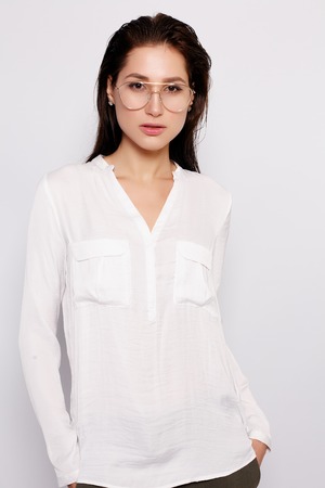 Pretty young girl in white blank t-shirt, wearing glasses, empty wall, studio portrait. Smiling brunette woman in eyeglassesの写真素材