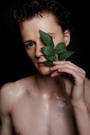 people, skincare and beauty concept - Wet young man with black hair on a black background. Portrait...