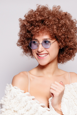 Portrait of smiling young black woman. Portrait of a beautiful young woman with African American afro haircut and glamor makeup. Studio shot. Attractive girl wearing eyeglasses.の写真素材