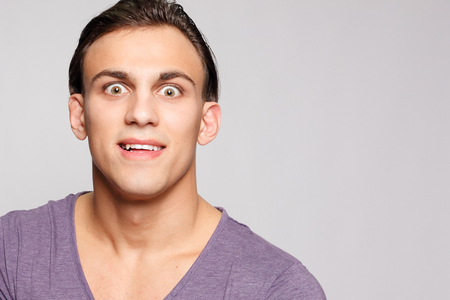 emotion, advertisement and people concept - Handsome young man on grey background looking at camera. Portrait of sexy man. Happy guy smiling.の写真素材