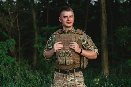 Soldier man standing against a field. Portrait of happy military soldier in boot camp. US Army...