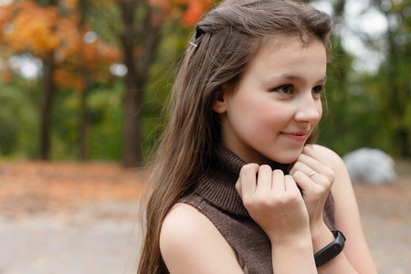 childhood, season and people concept - happy little girl with fallen maple leaves at autumn parkの写真素材