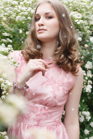 Close up portrait of a beautiful girl in a pink vintage dress standing near colorful flowers. Art work of romantic woman .Pretty tenderness model looking at camera.の写真素材