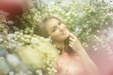 Close up portrait of a beautiful girl in a pink vintage dress standing near colorful flowers. Art work of romantic woman .Pretty tenderness model looking at camera.の写真素材