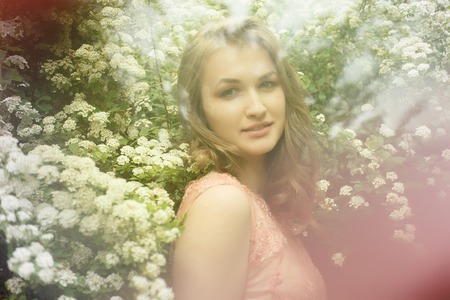 Close up portrait of a beautiful girl in a pink vintage dress standing near colorful flowers. Art work of romantic woman .Pretty tenderness model looking at camera.の写真素材