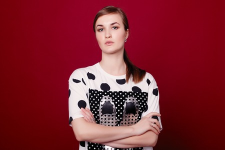 Adorable young woman with dark-brown hair laughing on claret background. Studio portrait of smiling european female model expressing positive emotions.の写真素材