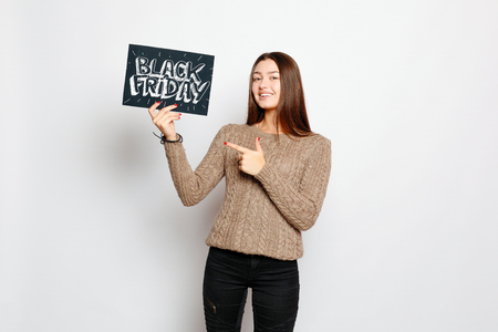 shopping, retail, black friday, sale, shopping and people concept - Young smiling brunette girl is holding a black friday sign. Black Friday sale.の写真素材