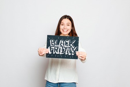 shopping, retail, black friday, sale, shopping and people concept - Young smiling brunette girl is holding a black friday sign. Black Friday sale.の写真素材