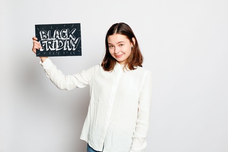 shopping, retail, black friday, sale, shopping and people concept - Young smiling brunette girl is...