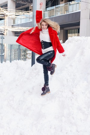 winter, fashion, people concept - fashion Portrait of a beautiful young woman walks around the city smiling red fur coat close-up snowflakes cold winter, breathe fresh air at frost winter day. sunsetの写真素材