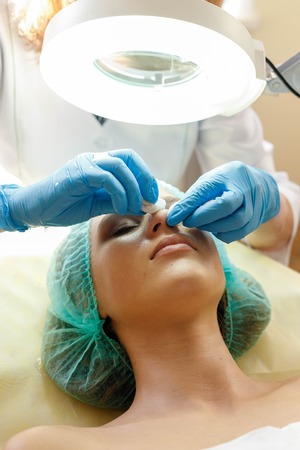 people, beauty, spa, cosmetology and technology concept - Cosmetologist makes the procedure microcurrent therapy of the facial skin of a beautiful, young woman in a beauty salonの写真素材