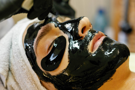 people, beauty, spa, cosmetology and technology concept - Spa salon. The cosmetologist puts a mask on the face of a young man.の写真素材