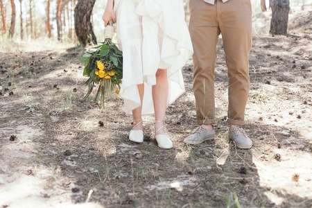 Wedding walk in the pine forest. Sunny day. Wedding couple in the forest. Beautiful Bride and groom on a walk. White wedding dress. Bouquet of peonies and hydrangeas.の写真素材