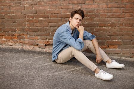 Young hipster sits in his blue denim button up shirt showing an unlabeled white cotton t-shirt...