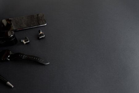 Accessories for men's beauty on a monochromatic background. black pen, black smart watch, smartphone and wireless headphones on dark background. View from above. Minimalist black trend 2020.の写真素材