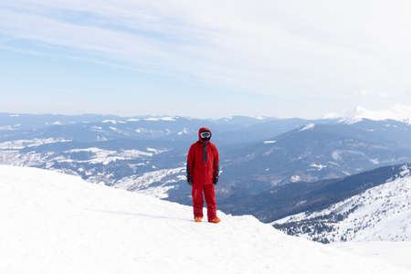 winter, leisure, sport and people concept - Man snowboarding in the mountains. Snowboarder resting on mountain top on a background of blue sky. Ski resort.の写真素材