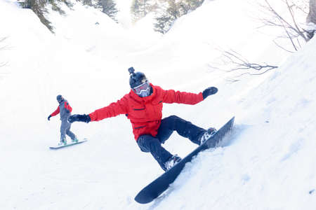 winter, leisure, sport and people concept - Man snowboarding in the mountains. Snowboarder resting on mountain top on a background of blue sky. Ski resort.の写真素材