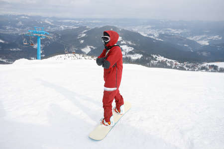 winter, leisure, sport and people concept - Man snowboarding in the mountains. Snowboarder resting on mountain top on a background of blue sky. Ski resort.の写真素材