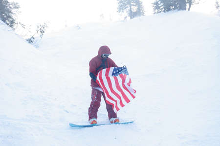 winter, leisure, sport and people concept - Man snowboarding in the mountains. Snowboarder resting on mountain top on a background of blue sky. Ski resort.の写真素材