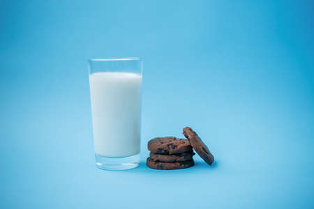 Cookies with chocolate chips on a plate on a table and a glass of milkの写真素材