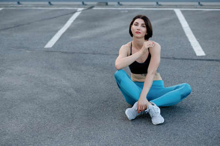 Strong young woman stretching with skipping. Fitness female athlete exercising outdoors.
