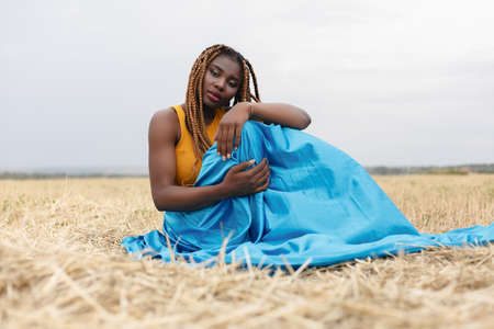 african american young woman having fun outdoors at sunset. laughing girl on field. beautiful young african american woman with pigtailsの写真素材