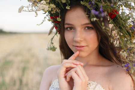 Nature portrait. Closeup of beautiful woman in dress is keeping wheat crop in her hands while...