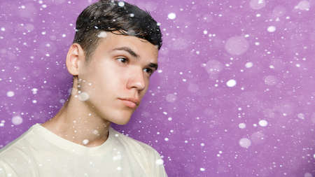 snow, winter, christmas, people, beauty concept - Indoor shot of handsome guy with brooding expression, stands against purple background, free space aside. People and emotions. 16: 9 panoramic format.の写真素材