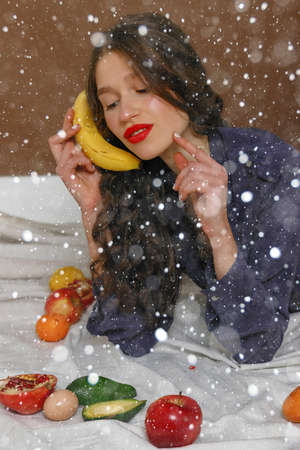 snow, winter, christmas, people, beauty concept - Young woman in group of fruit. Healthcare and healthy nutrition concept. apple on my head and a smile. 16: 9 panoramic format.の写真素材