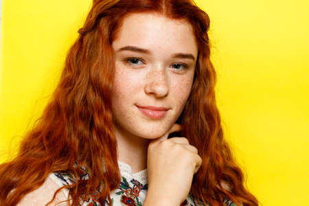 Indoor portrait of excited curly woman with trendy makeup. Ginger caucasian young lady smiling on yellow background.の写真素材