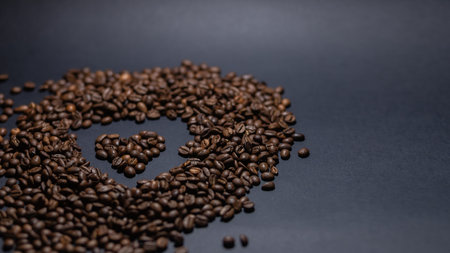heap of coffee beans on black background. Coffee beans pile isolated on black background. Culinary coffee background. heart shaped coffee beans top viewの写真素材