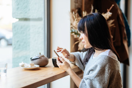 Image of young female reading sms on the phone in cafeの写真素材
