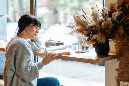 Reading sets me free from boredom. Young student girl at cafe reading book.の写真素材